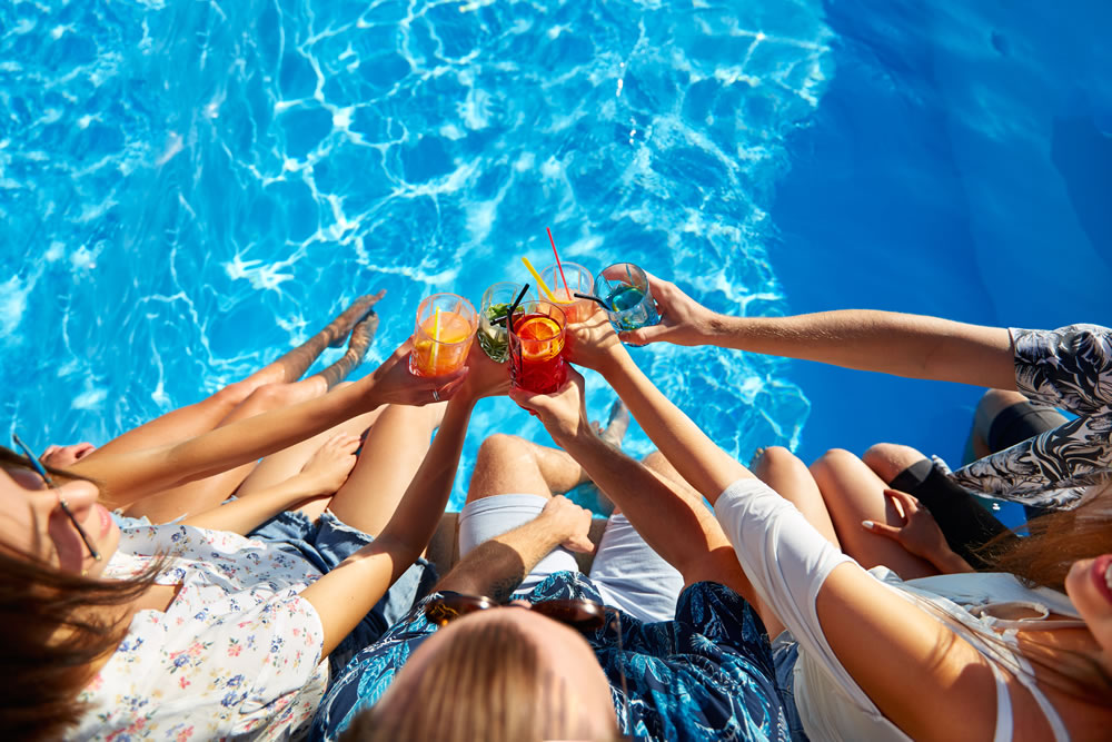 People toasting drinks at a luxury villa poolside party