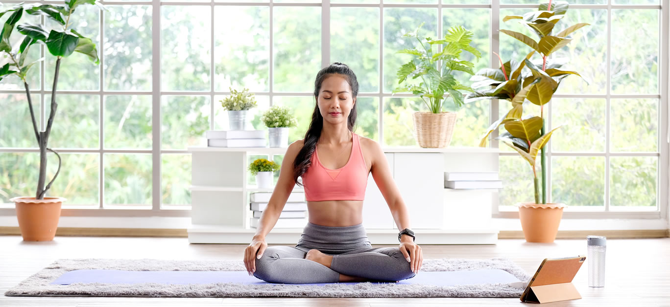 Asian woman practice yoga meditation exercise at home by online training class