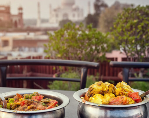 Aloo Gobi and Sabji Masala Traditional Indian food in metal plates on rooftop restaurant with Taj Mahal view in Agra Uttar Pradesh India