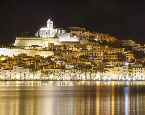 Skyline of Ibiza Dalt Vila downtown at night with light reflections in the water