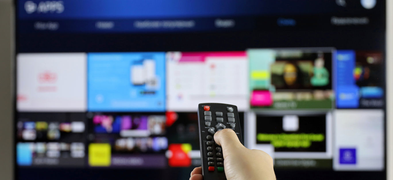 Female hand with remote controller on smart TV screen background. Woman choosing streaming services, watching movies