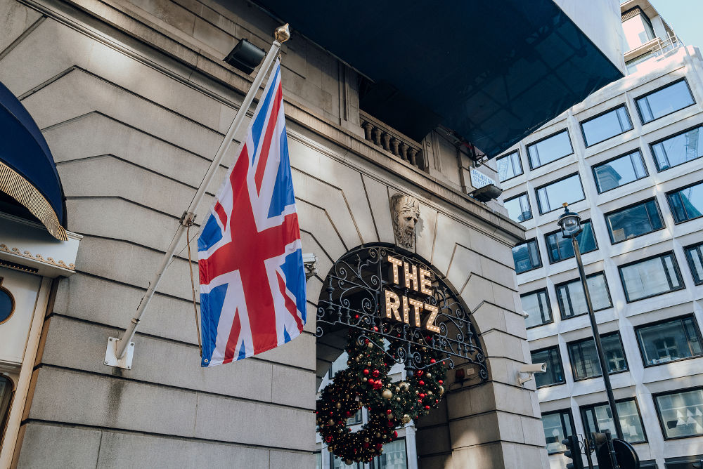 Sign outside The Ritz, Londons most iconic hotel, next to the Union Jack flag on a pole.