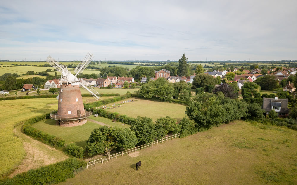 An aerial view of the village of Thaxton in the heart of Essex, England with its landmark traditional old English windmill.