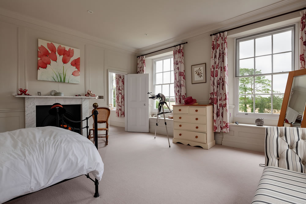 Bedroom in English period home with traditional yet sympathetically modern decor, fireplace with marble surround and georgian style multi pane windows