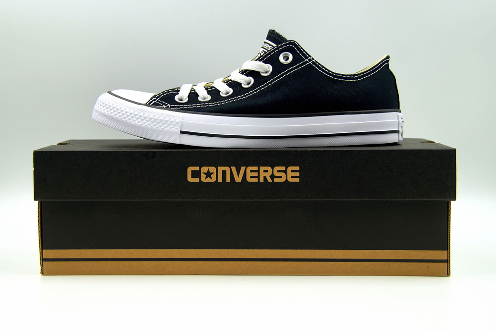 Black Chuck Taylor Converse All Star low top standing on a retail box, against a white background.
