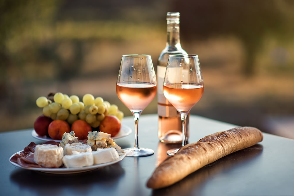 Bottle of rose wine and two full glasses of wine on table in heart of Provence