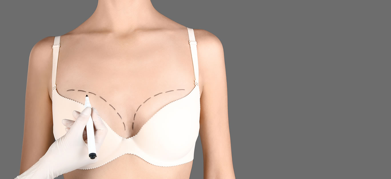 Doctor drawing marks on patient's breast for cosmetic surgery operation against gray background, closeup