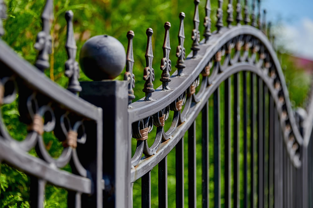 Image of a beautiful decorative metal wrought-iron fence with artistic forging. Metal fence close-up.