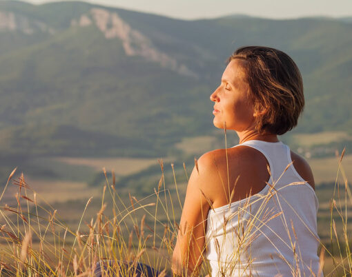 Sitting in meditation pose woman enjoyed with gently shining sunrise