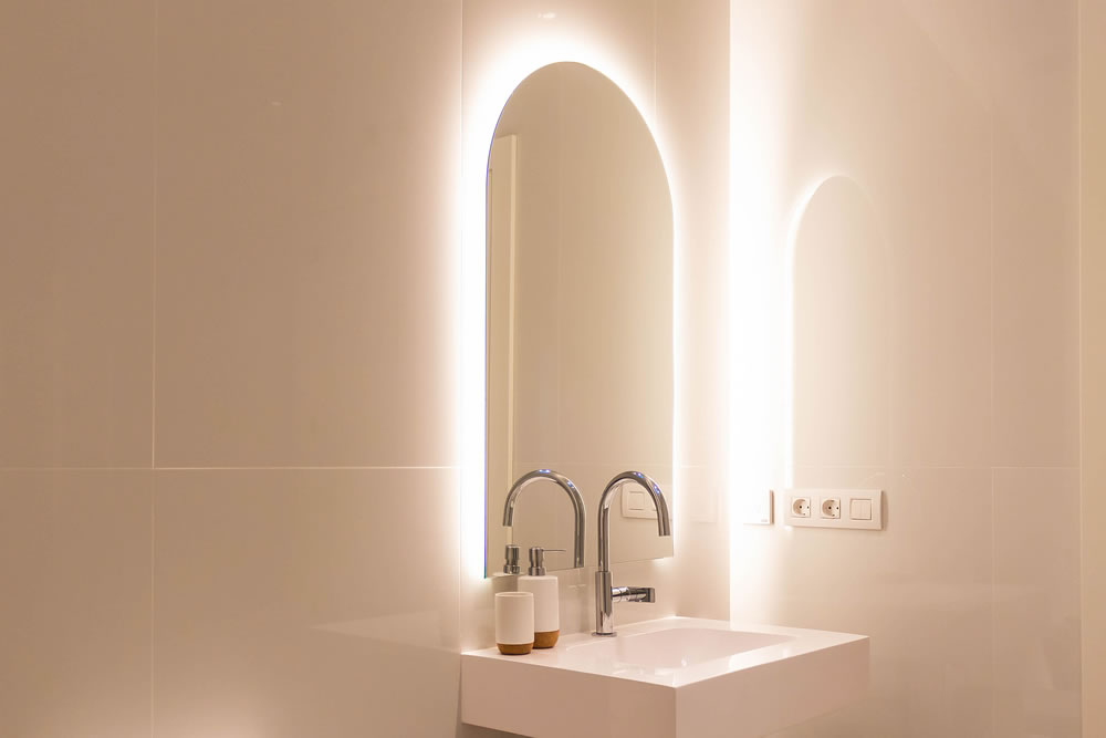Minimal white luxury bathroom sink with arch-shaped mirror and integrated LED