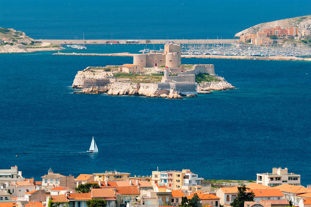 View of Marseille town and Chateau d'If castle famous historical fortress and prison on island in Marseille bay with yacht in sea. Marseille, France