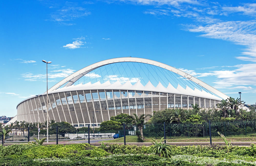 Early morning green vegetation against Moses Mabhida Stadium and blue cloudy sky background in Durban South Africa