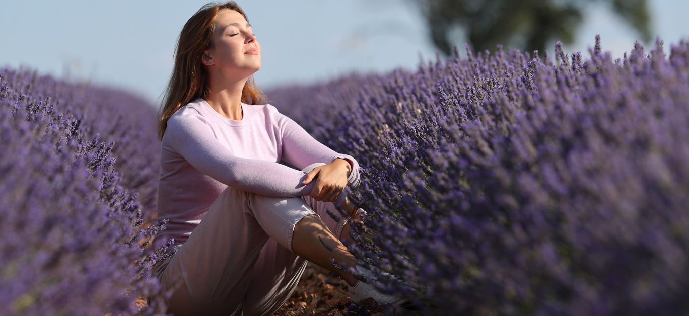 Relaxed woman breathing fresh air sitting in a lavender field a sunny day