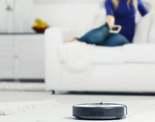 Robotic vacuum cleaner cleaning the room while woman resting on sofa