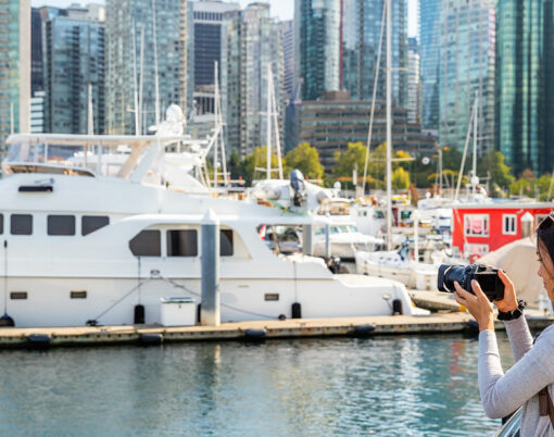 Vancouver Canada tourist woman taking picture with camera at Coal Harbour on summer holidays in canadian city.