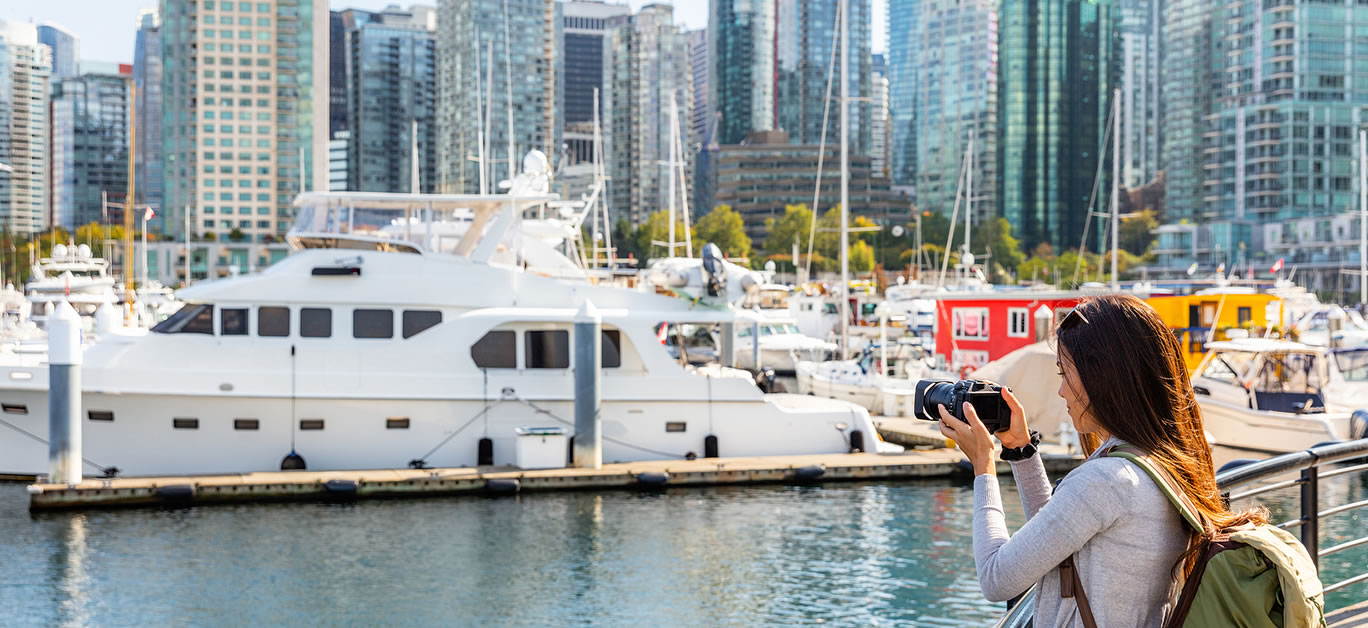 Vancouver Canada tourist woman taking picture with camera at Coal Harbour on summer holidays in canadian city.
