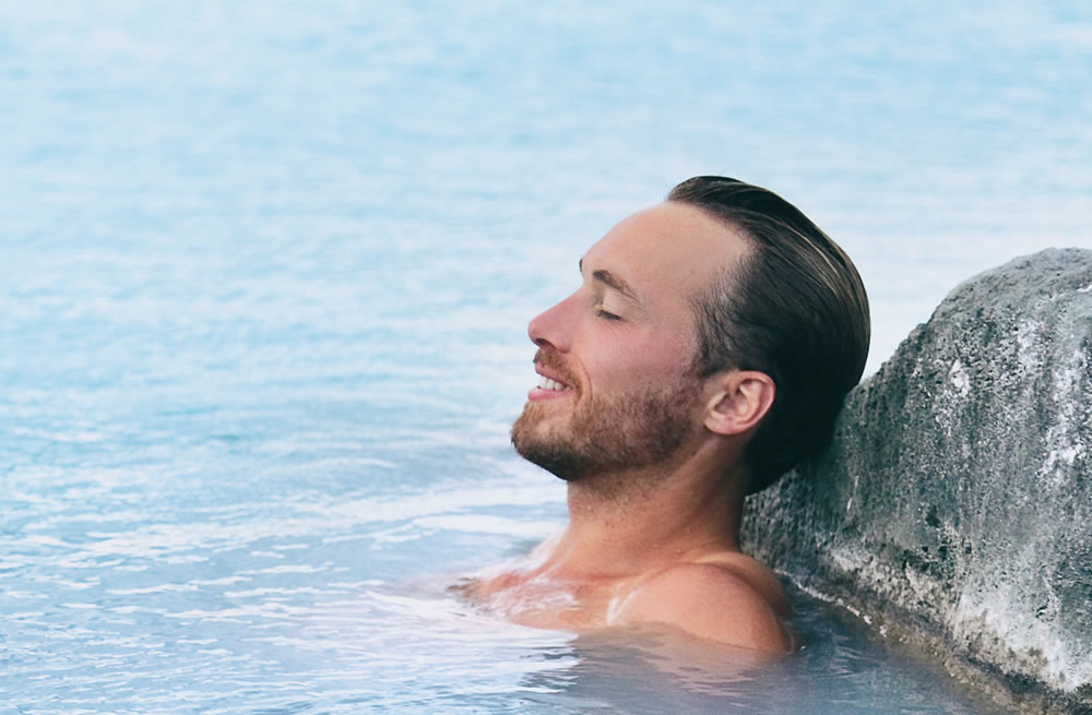 Wellness Spa man relaxing in hot springs outdoor at luxury resort spa retreat