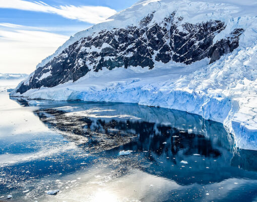 Antarctic mountain landscape with cruise ship standing still on the surface of Neco bay, Antarctica