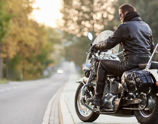 Save Download Preview Back view of bearded biker with long hair in black leather jacket sitting on cruiser motorcycle