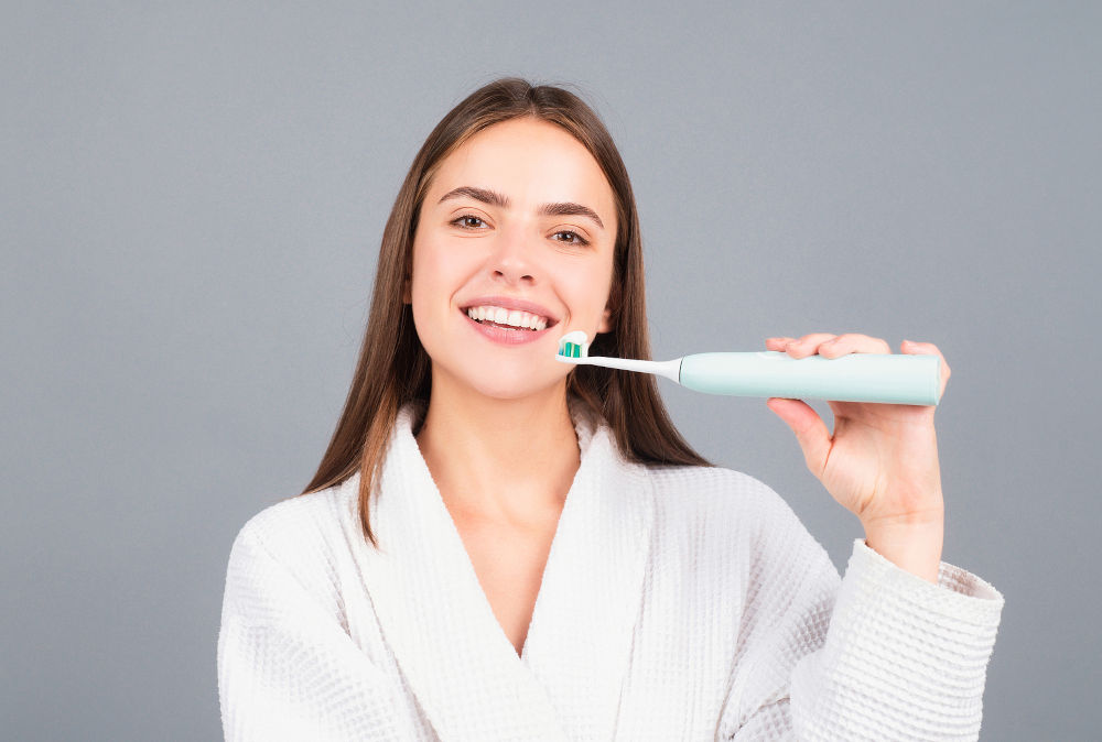 Electric toothbrush. Beauty portrait of a happy beautiful woman brushing her teeth with a toothbrush isolated background.