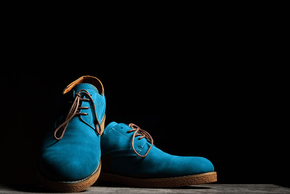 Festive blue shoes with laces on a black background with copy space.