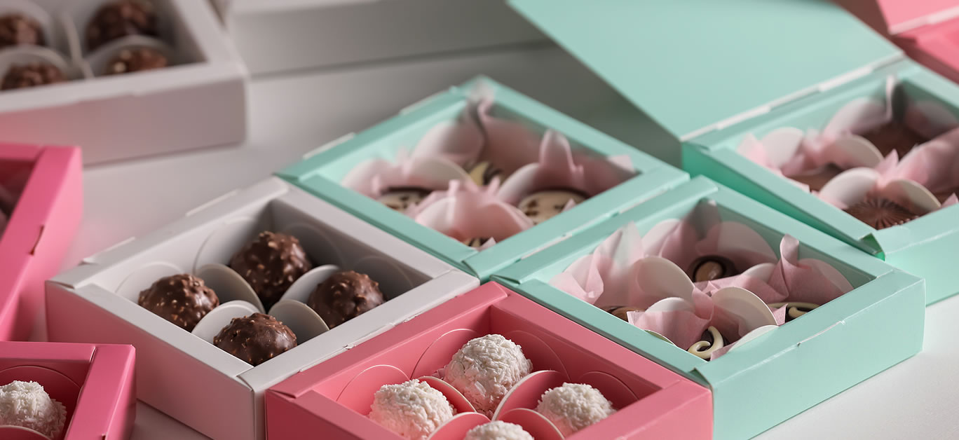 Boxes with delicious candies on white table, closeup. Production line