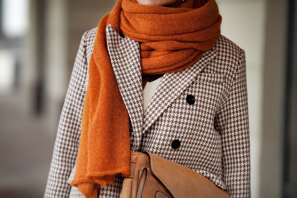 Close up knitted wool ochre scarf and double breasted houndstooth jacket with buttons. Stylish fashion trend details