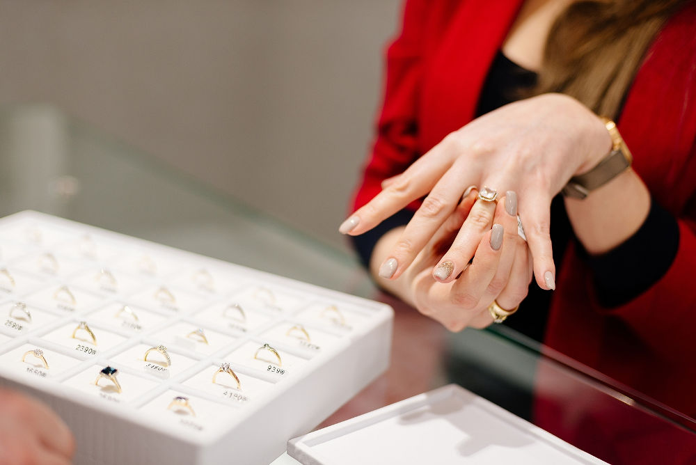 Female seller in a luxury jewelry store presents a ring. Buying a engagement ring. Jewelry store. Woman jeweler.