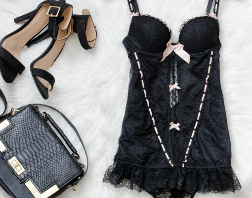 Black lace corset shoes handbag on a white fur. Fashionable concept top view