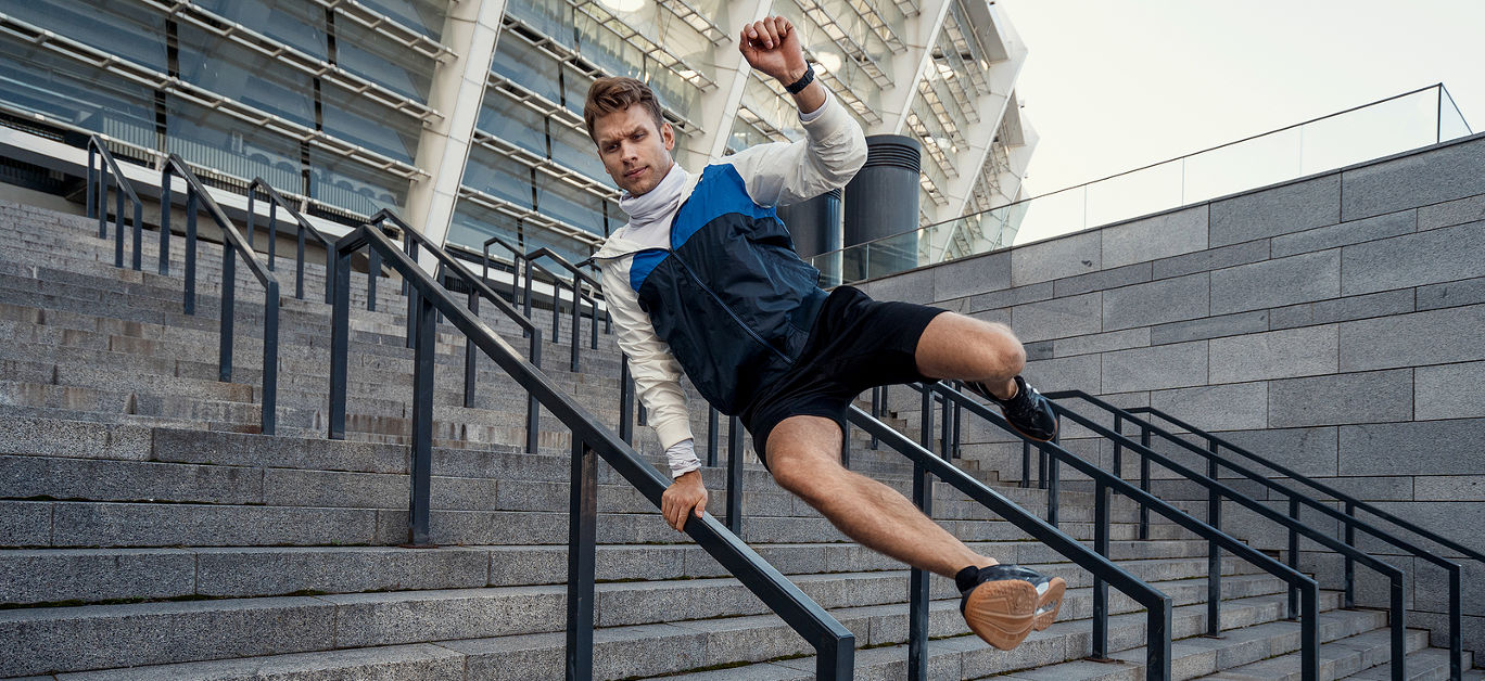 Full length portrait of sporty man jumps over the railing in the city.