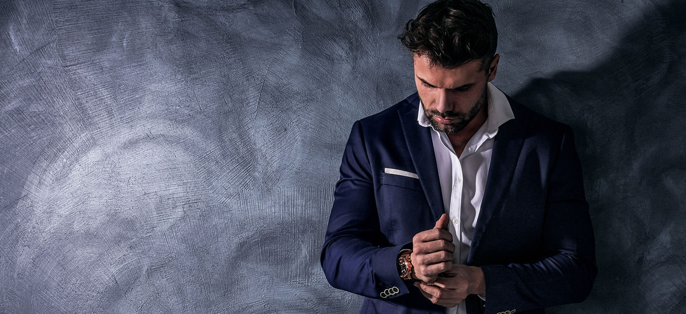 Handsome, confident, elegant man posing in fashionable suit, wearing luxury hand watch. Copy space. Male model.