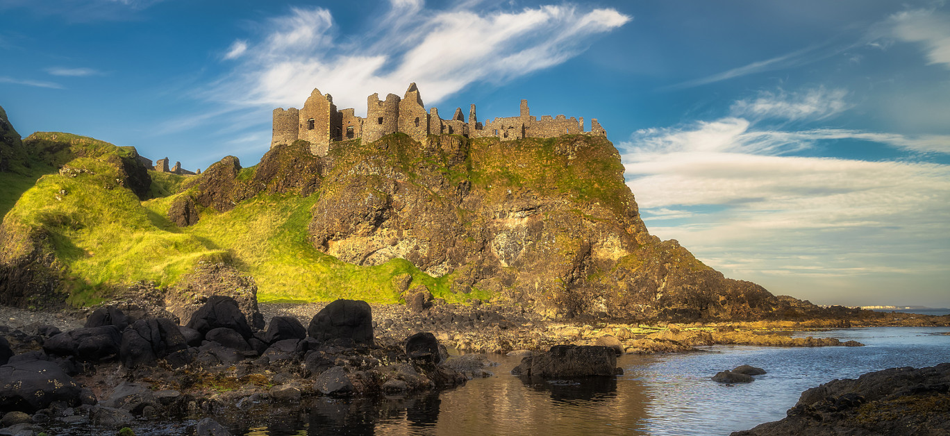 View from a shoreline on Dunluce Castle nested on the edge of cliff, part of Wild Atlantic Way, Northern Ireland. Filming location of popular TV show