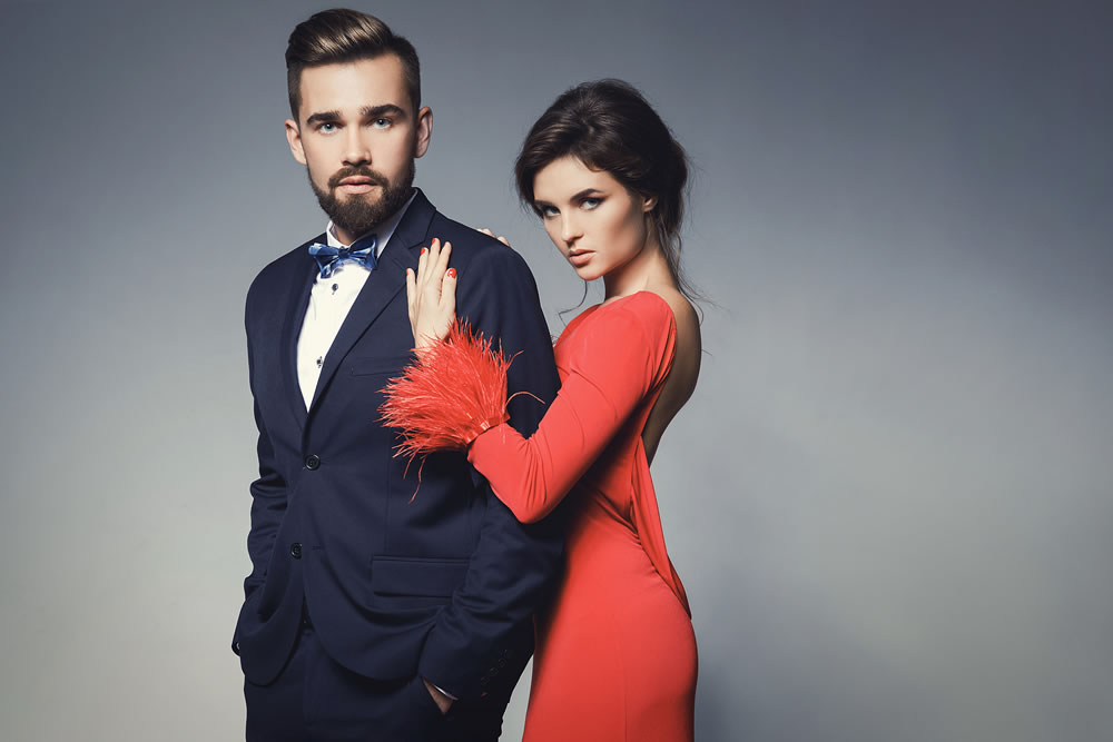 Woman in beautiful red dress and man wearing blue classical suit with bow tie.