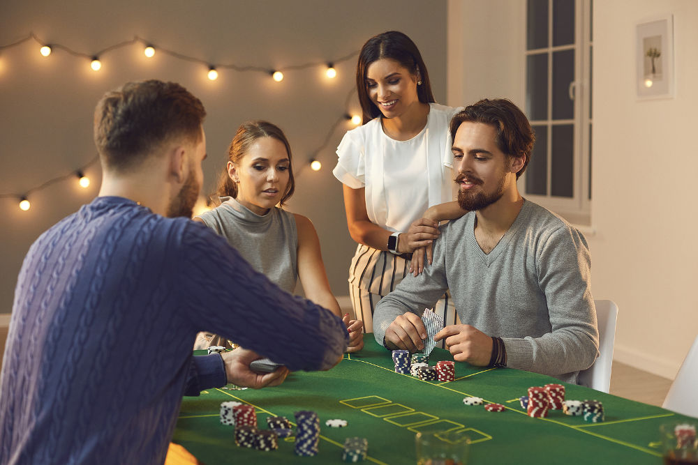 Group of young friends awaiting for card from deck during betting and playing poker
