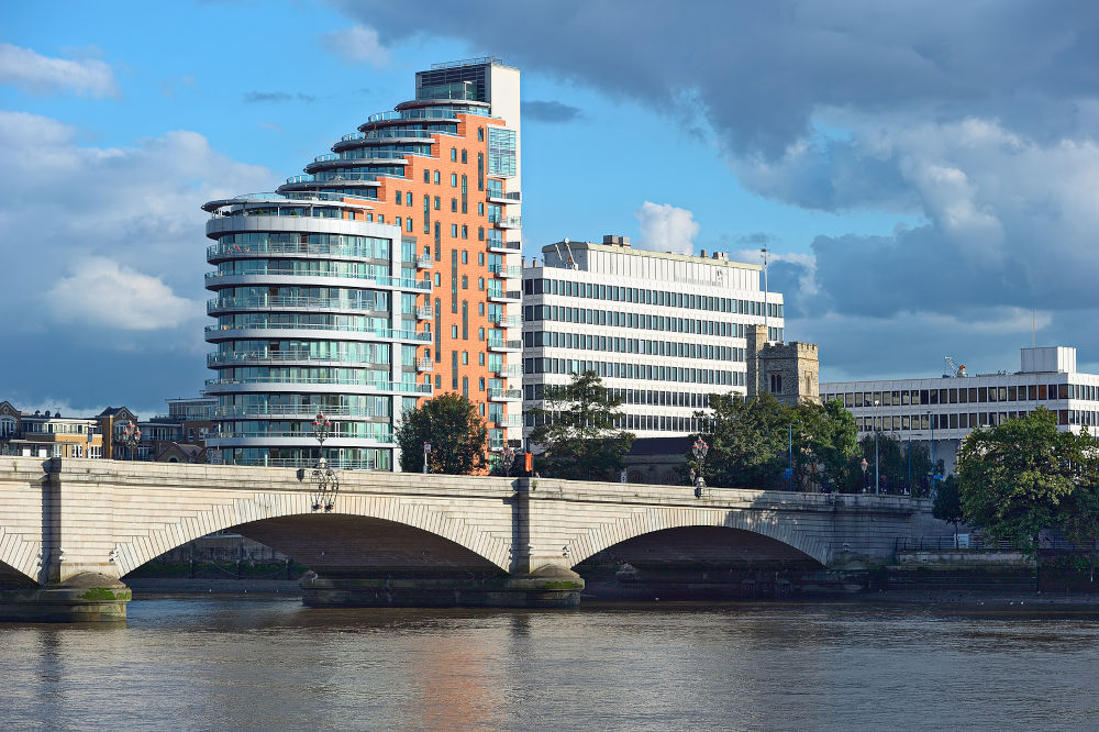 Putney Bridge on the River Thames London UK Europe overshadowed by St Mary's Church itself dominated by tower blocks