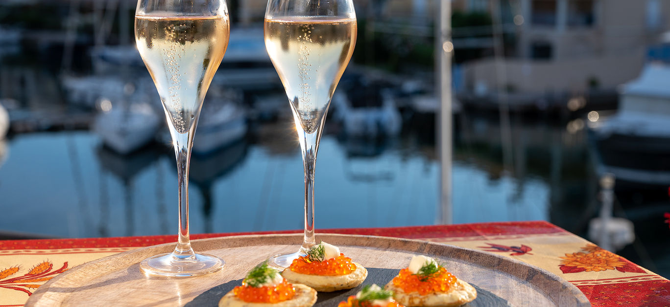 party with two glasses of white cold champagne, bliny with red caviar and view on Port Grimaud near Saint-Tropez