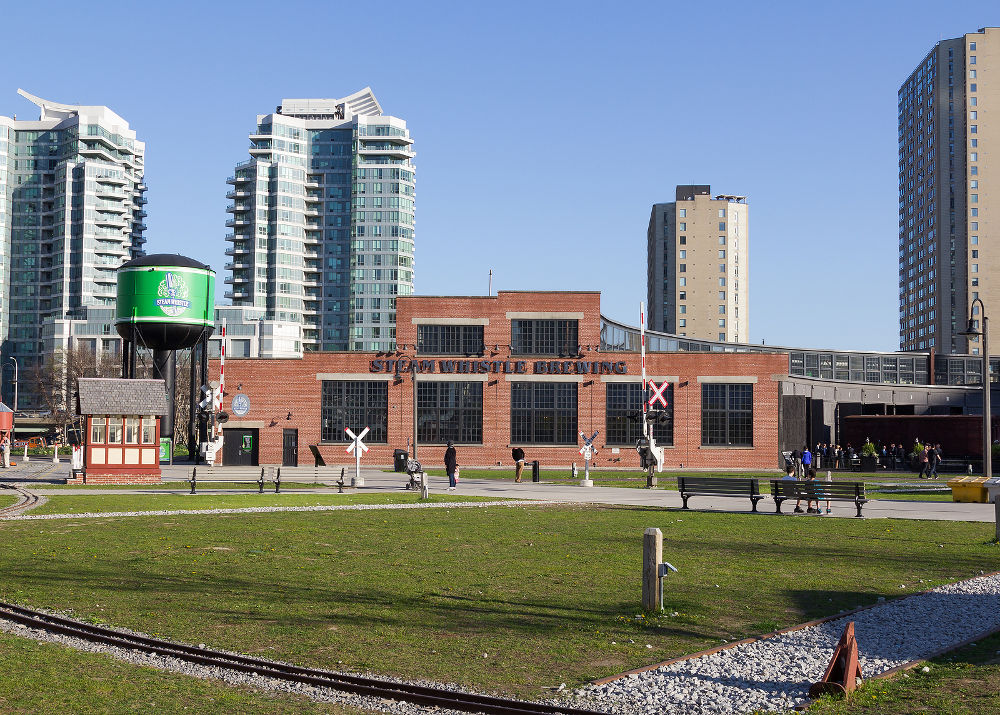 The outside of the Steam Whistle Brewing building during the day and people can be seen outside the building