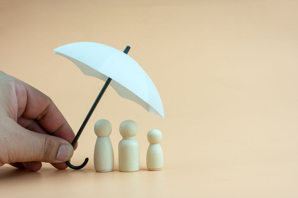 White umbrella with wooden family peg dolls for protection with copy space