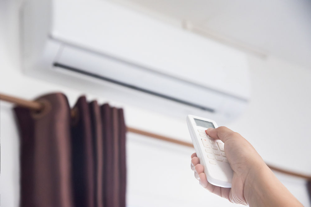 A man use remote controller to set air conditioner temperature in the room