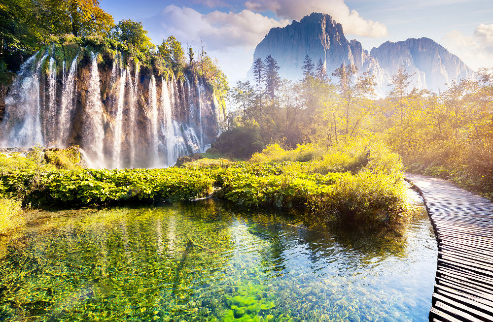 Majestic view on waterfall with turquoise water and sunny beams in the Plitvice Lakes National Park