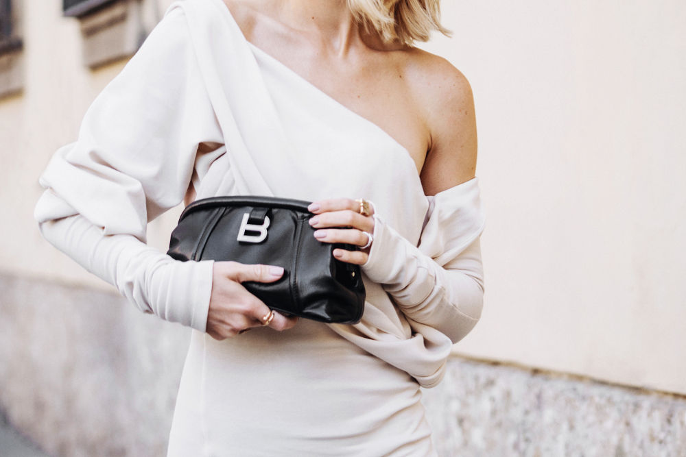 woman wears Balenciaga black editor clutch, street style details