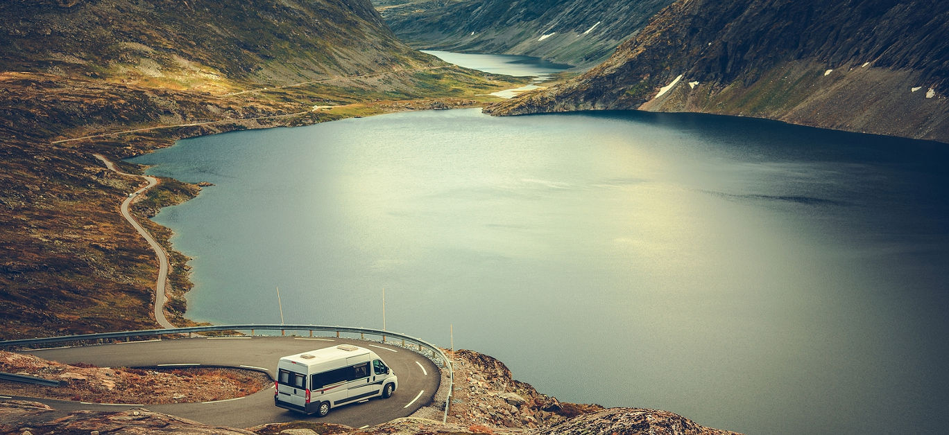RV Camper Scenic Road Trip. Raw Norwegian Landscape and the Camper Van Recreational Vehicle on the Winding Mountain Road near Famous Village of Geiranger.