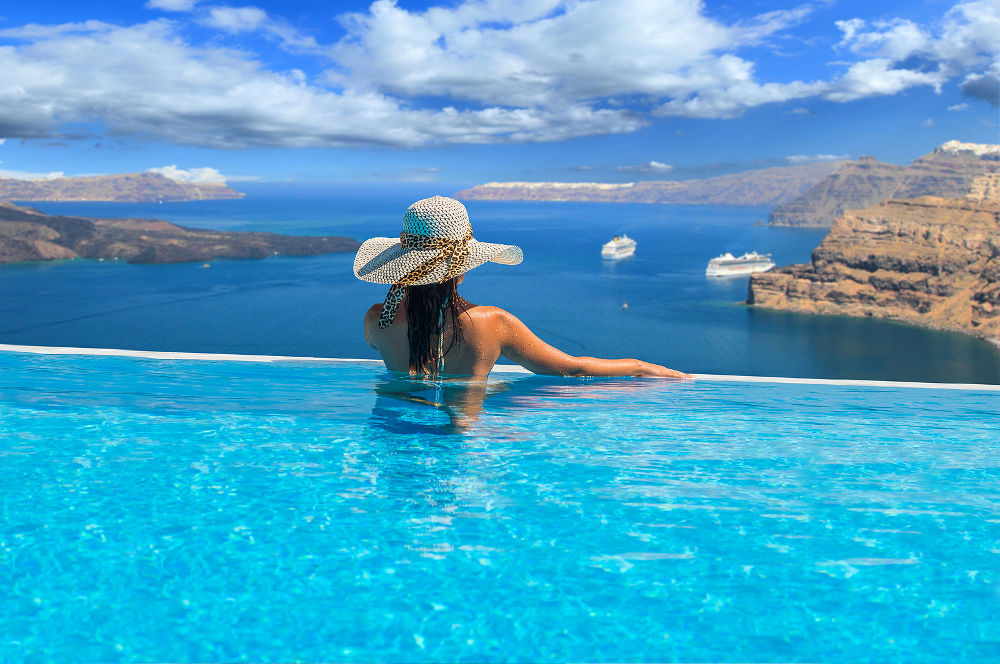 Woman enjoying relaxation in pool and looking at the view in Santorini Greece