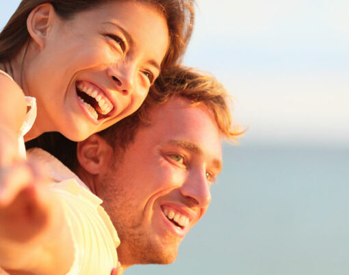 Beach couple laughing in love romance on travel honeymoon vacation summer holidays romance