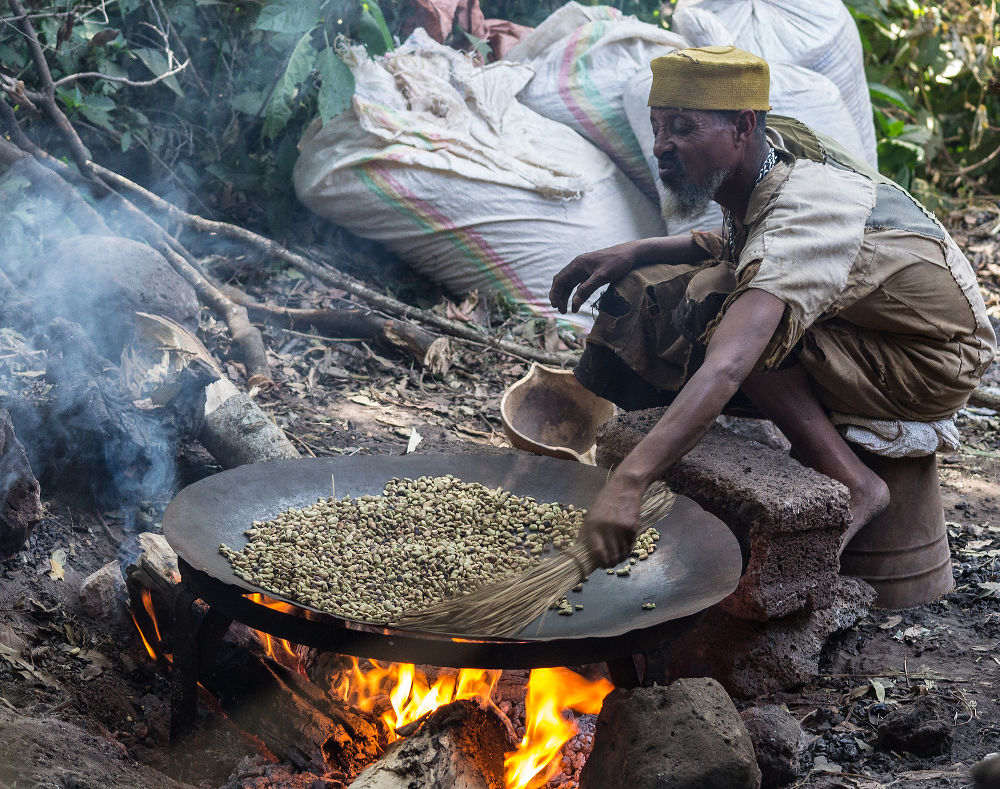roasting coffee beans in a large pan placed on a wood fire in Bahir Dar Ethiopia