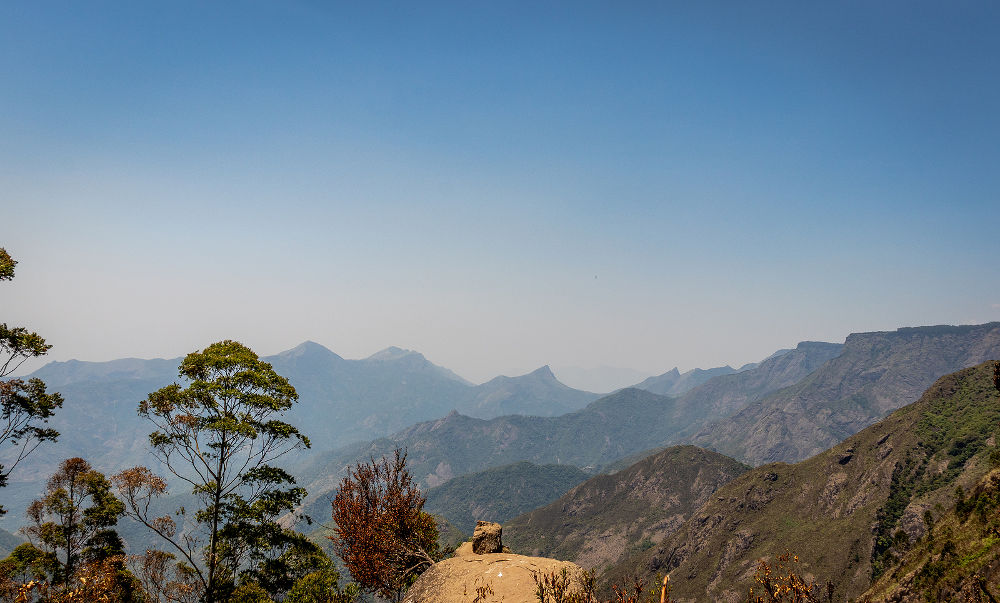 Single rock with hill range and blue background image is taken at echo point kodaikanal tamilnadu india.
