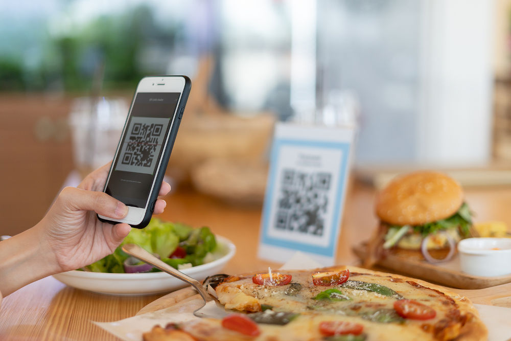 Woman use smartphone to scan QR code to pay in cafe restaurant with a digital payment without cash