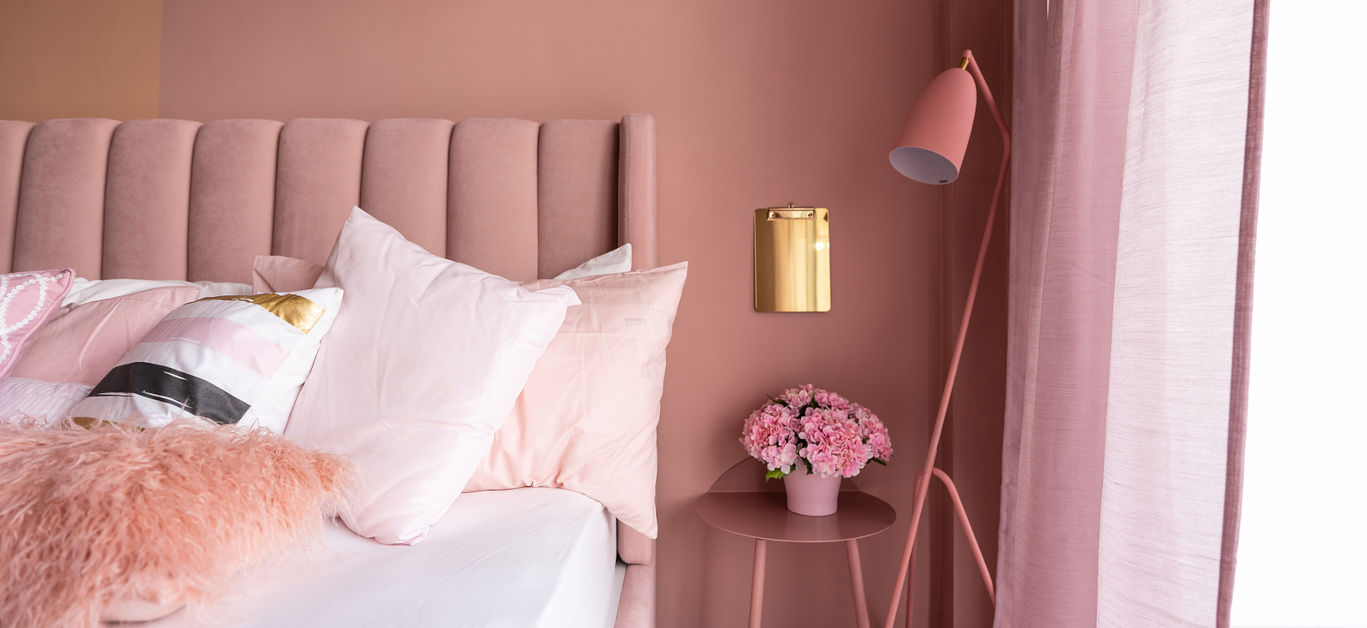 Cozy Pink Bedroom corner with baby pink velvet fabric bed decorated by blanket, pillows and pink floor lamp with two-tone pink painted wall