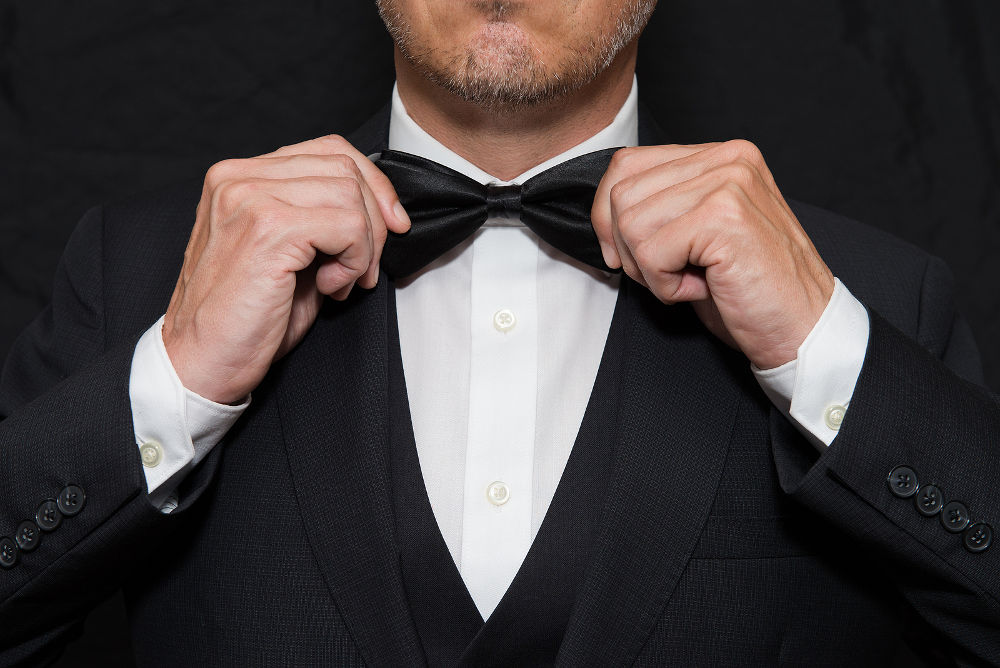 Close-up of a gentleman wearing Black Tie straightens his bowtie