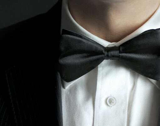 A close-up shot of a man straightening his tux.